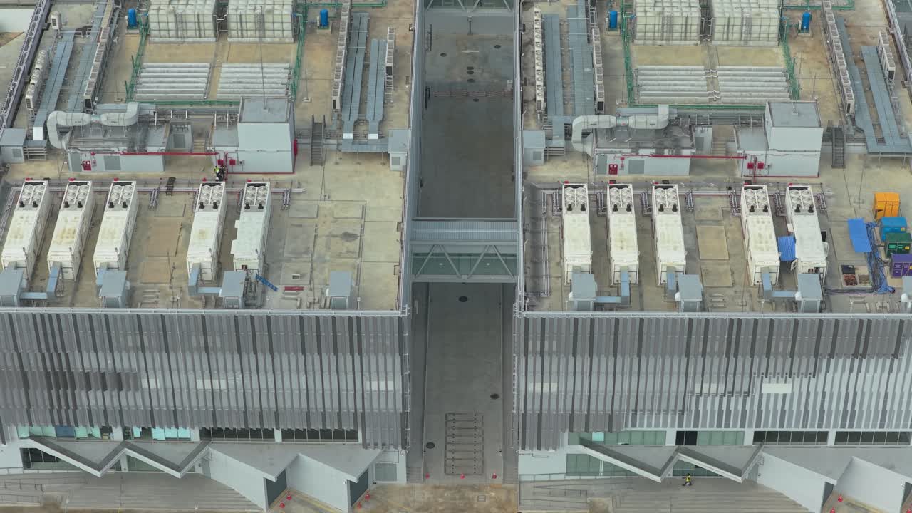 Top down aerial view of a large, modern data center building. Cooling systems and ventilation equipment are visible on the industrial rooftop