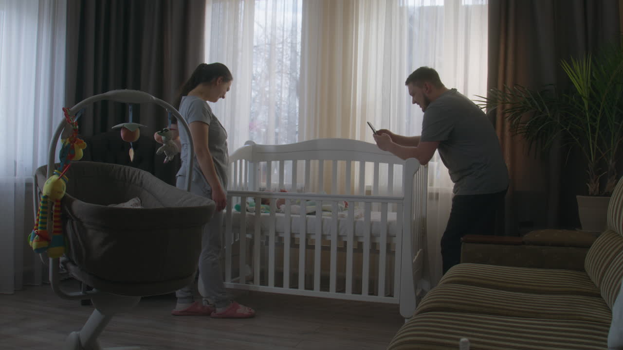 Parents looking at their newborn baby in a crib