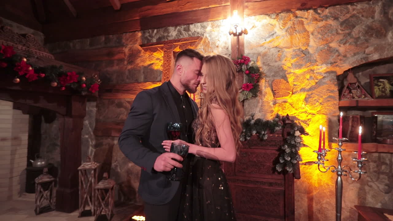 Loving pair hugging and caressing each other in beautiful room. Sweet couple in festive clothes celebrate Christmas eve.