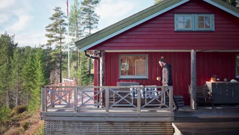 man walking in the porch of the red cabin in norway