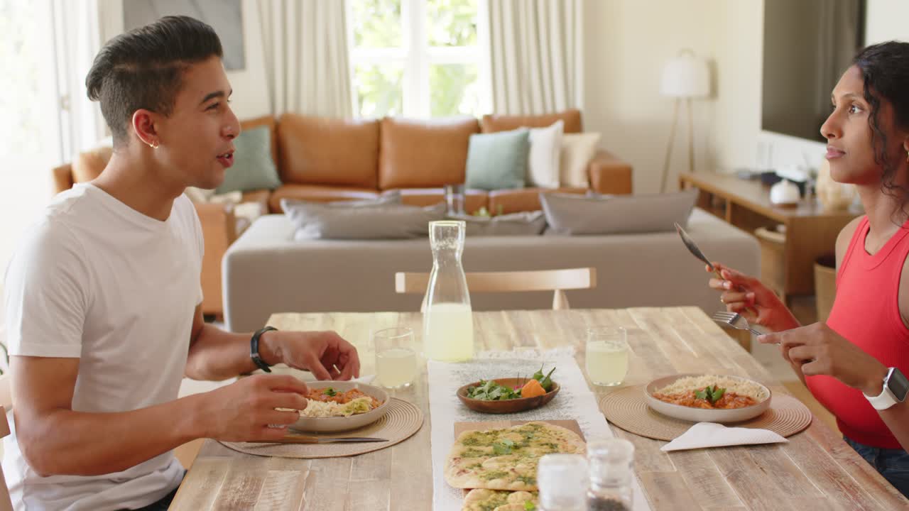 African American couple at home table, man seasoning bowl while woman starting meal with flatbreads