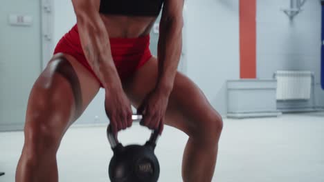 woman performing kettlebell squats in a gym