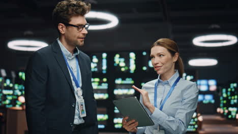 data center woman talking to it man in big cloud computing server farm closeup