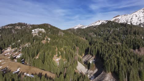 Astonishing-aerial-shot-of-Amden-Arvenbuel,-Switzeland,-with-mountainous-landscape-covered-with-green-alpine-trees-with-ice-capped-mountain-ranges-on-the-right-hand-side-of-the-shot