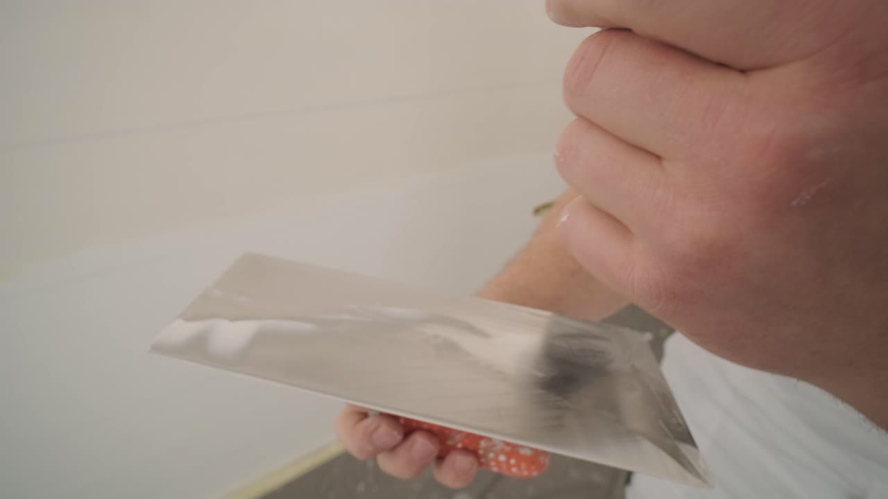 Man plastering the walls with finishing putty in room with putty spatula