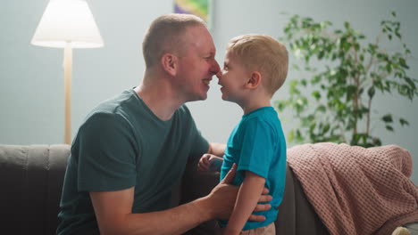 man plays with child, dad and son rub their noses