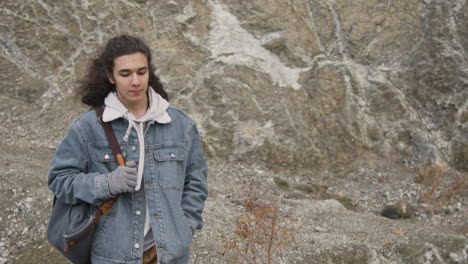 front view of a teenage boy with long hair and winter clothes on the mountain on a windy day