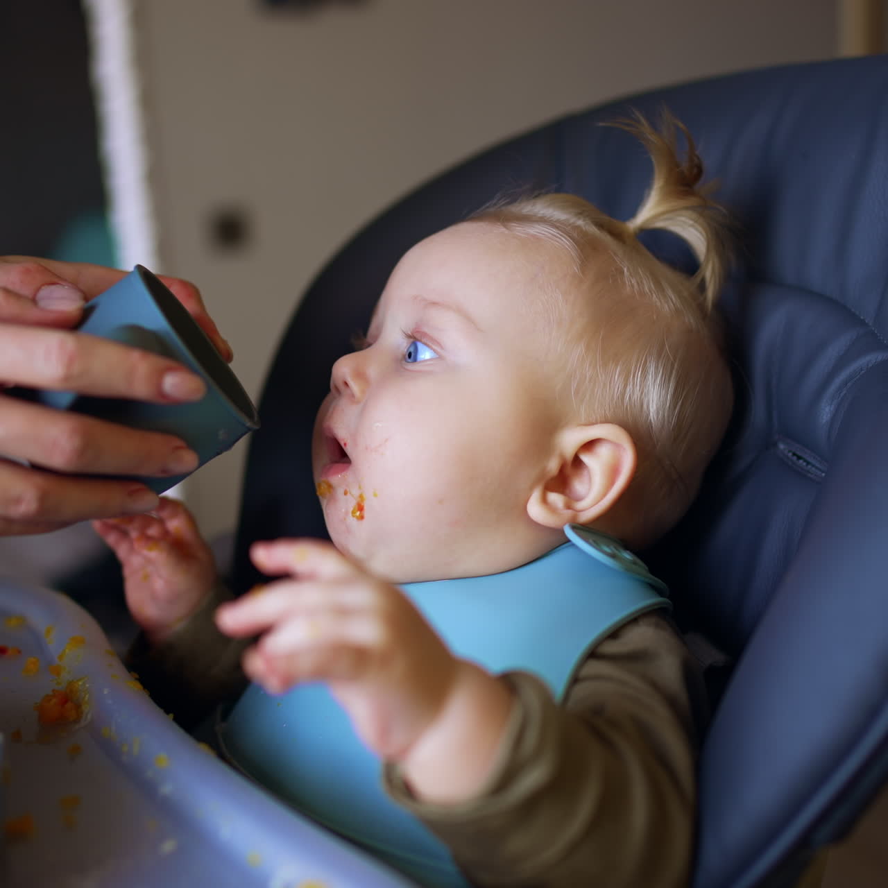 Mamá le da una taza a su bebé para que beba. Hora de comer para un niño pequeño en casa.