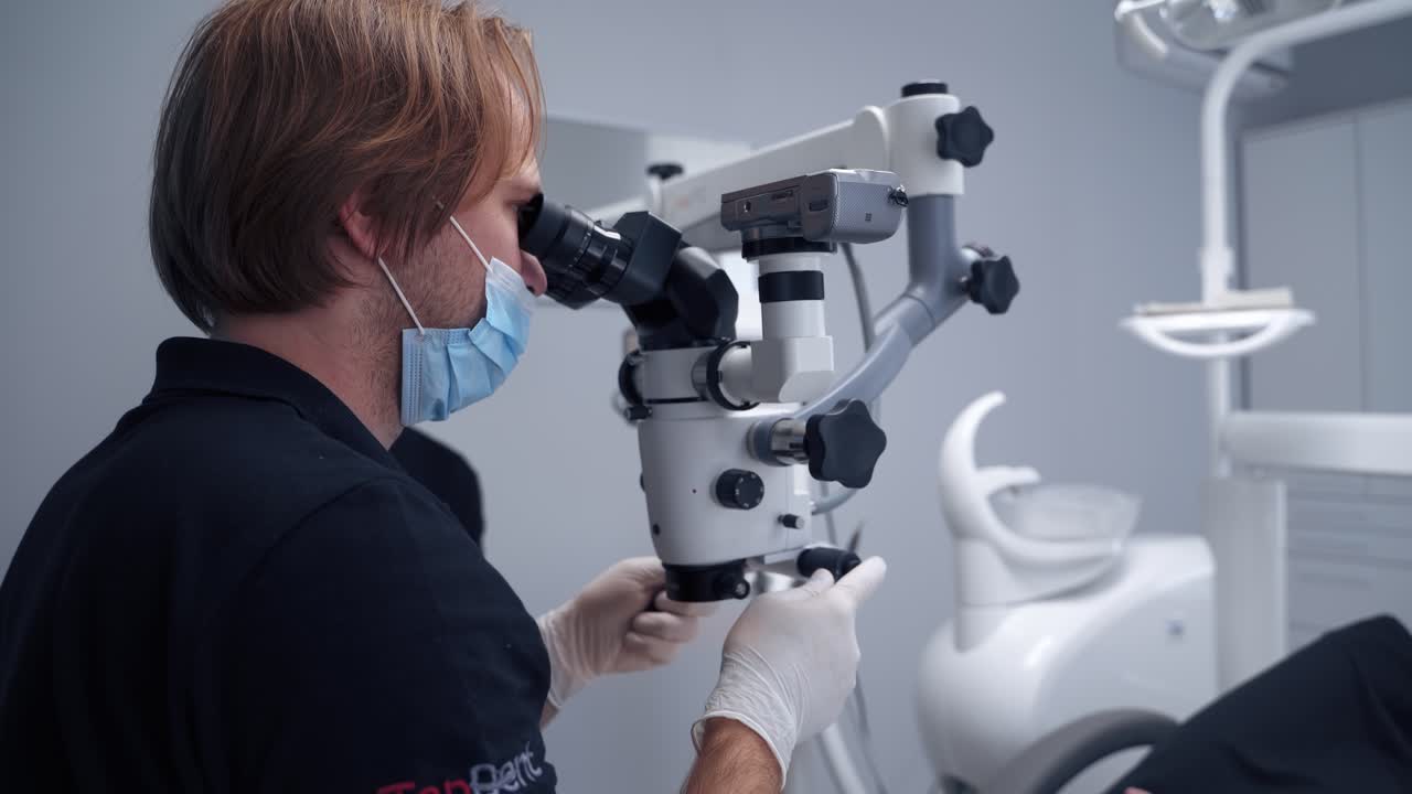 Modern technologies in dentistry. Stomatologist uses new equipment in his work. Male assistant helps the dentist in dental office.