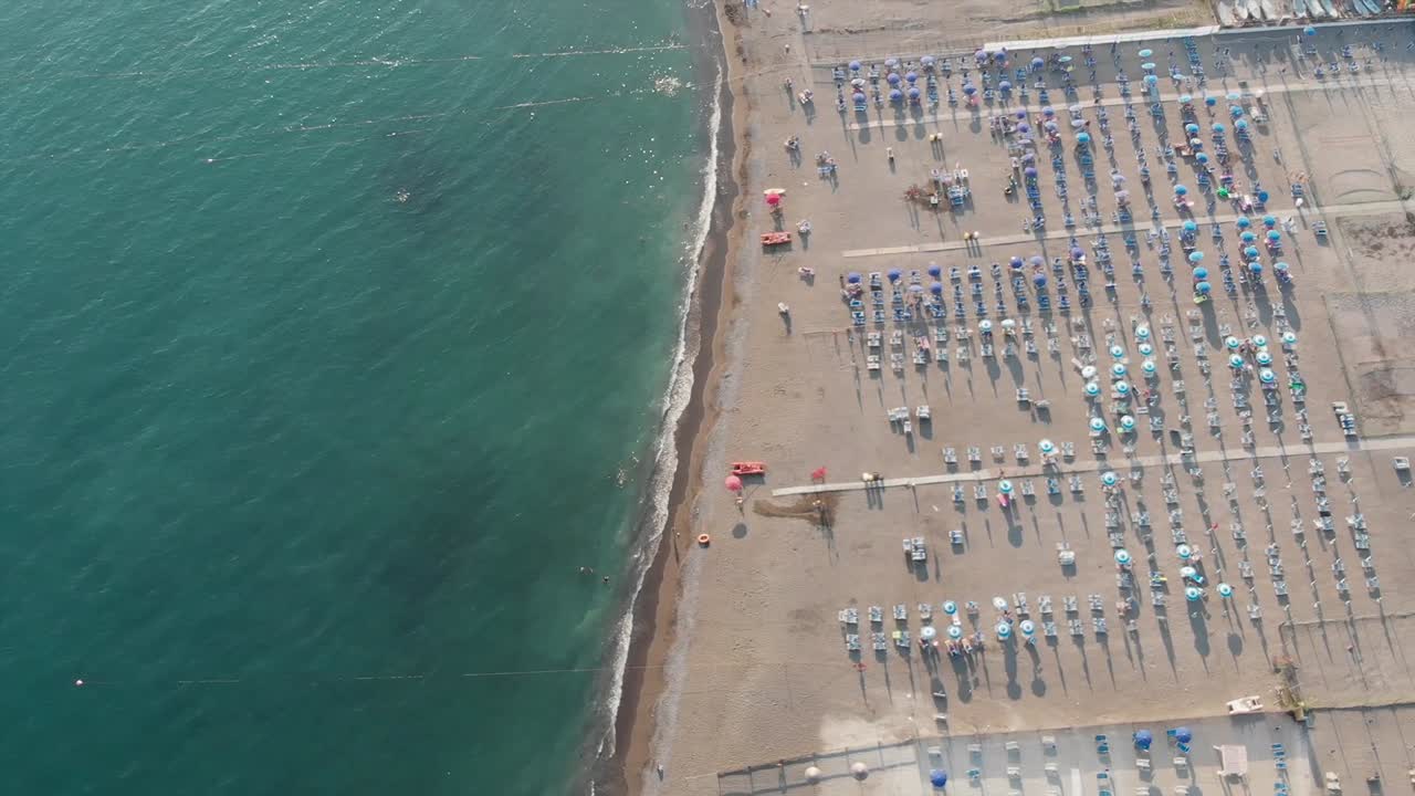 vista de pájaro de una playa de arena con tumbonas y sombrillas