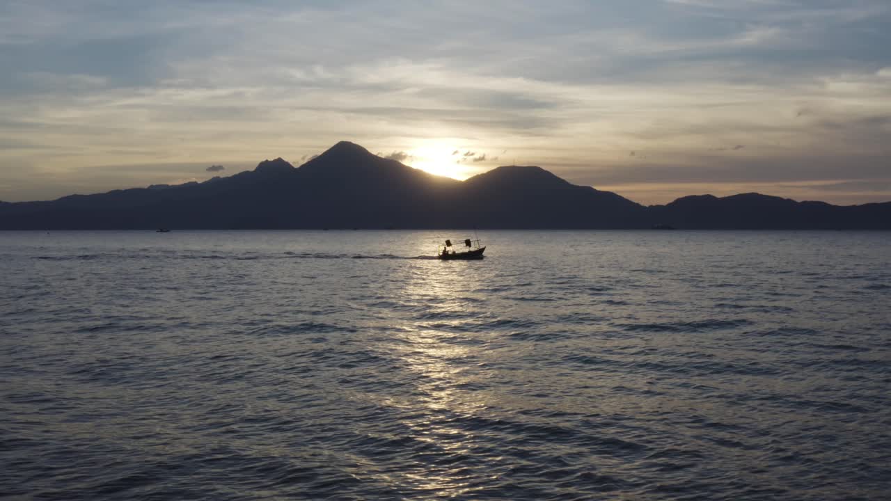 barco de pesca se dirige al océano al atardecer contra un hermoso paisaje montañoso en asia