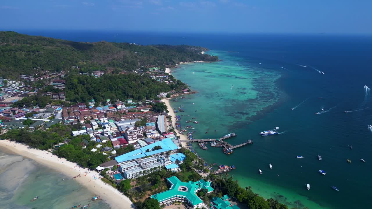 Turkisblåt vand, der omgiver en tropisk ø med frodig grøn vegetation i Thailand.