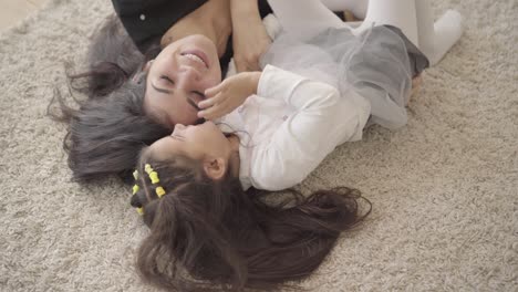 portrait of a smiling middle eastern young woman playing with her daughter at the soft carpet