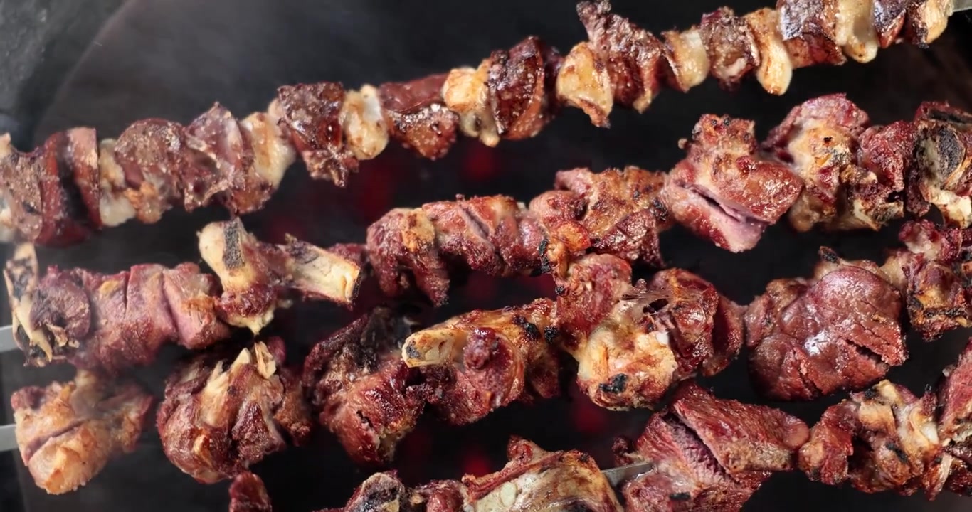 Deliziosi spiedini barbecue che cuociono su fiamme fumose in un vivace ambiente esterno