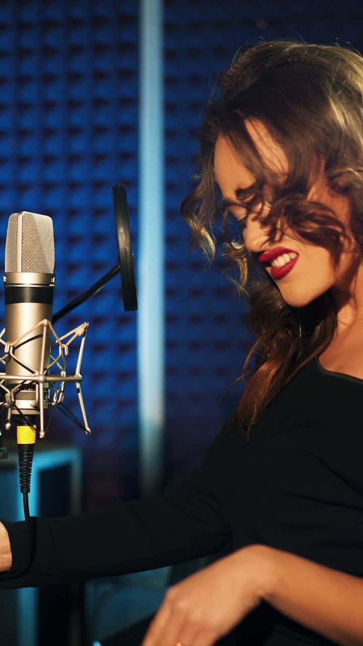 Girl singing to the microphone in a studio. Female vocal. Professional recording studio Vertical video