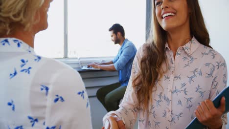 Female-executives-shaking-hands-while-interacting-with-each-other