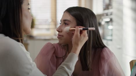 caucasian woman teaching daughter how to do make up for a party