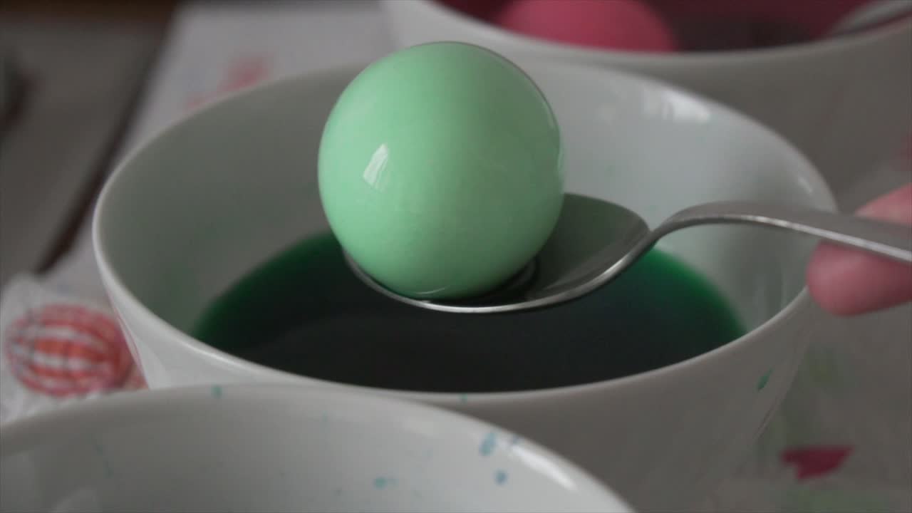 Close view of an eastern egg being painted in a bowl of water