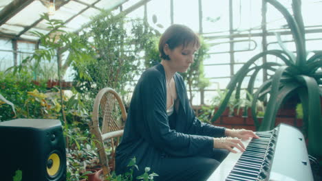 talented female musician playing keyboard in verdant greenhouse