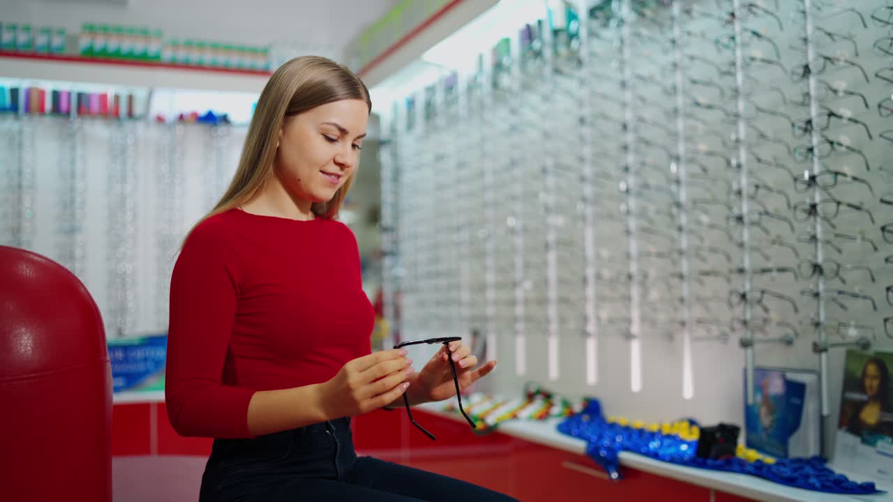 Woman examining eyeglasses. Happy woman choosing glasses at optical store