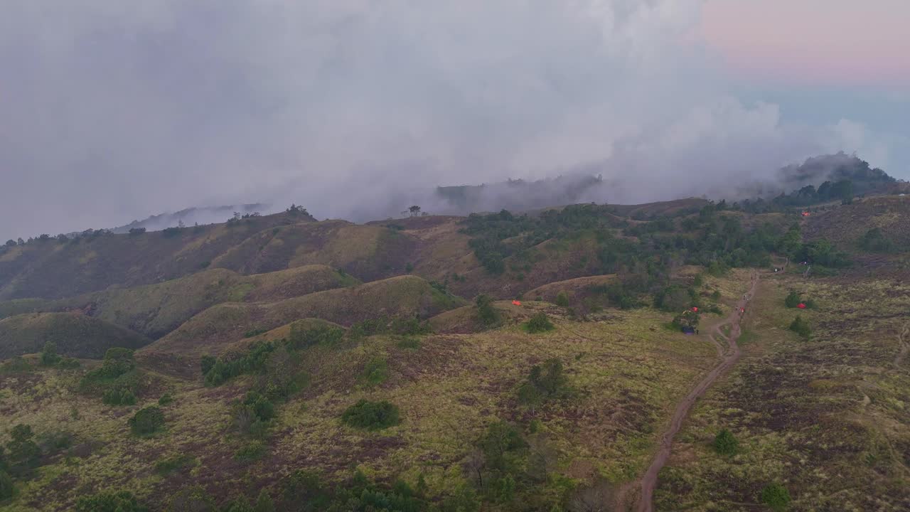 Drone footage of rolling mountain ridges cloaked in mist. A breathtaking natural landscape ideal for travel, nature, or meditation content. Mount Prau, Indonesia