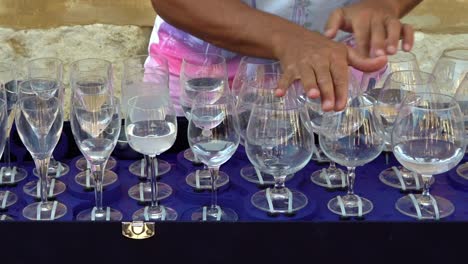 street musician plays a tune on glasses filled with water.