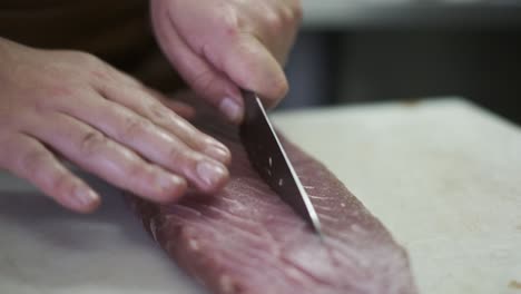 chef or cook cutting meat for cooking