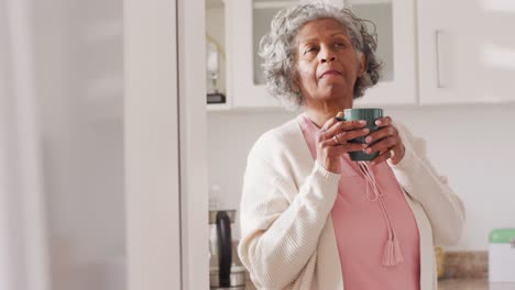 Glückliche-ältere-Afroamerikanische-Frau,-Die-Kaffee-In-Der-Küche-Trinkt