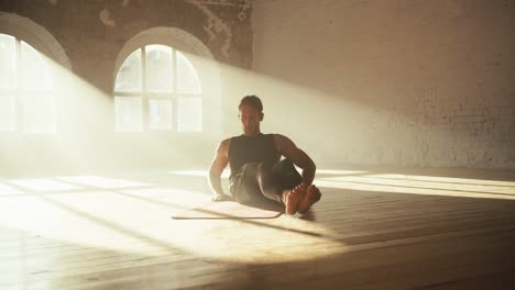 A-male-athlete-in-a-black-sports-summer-uniform-raises-his-legs-in-front-of-him-and-swings-them-to-the-left-and-right.-Exercises