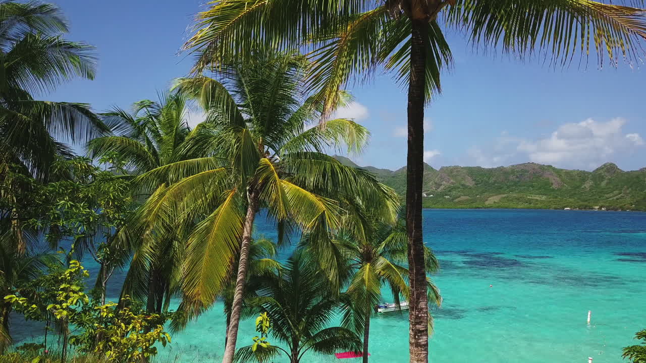 Máy bay không người lái hạ xuống trên vịnh ngọc lam yên tĩnh, hé lộ đường bờ biển nhiệt đới và dãy núi xanh dưới bầu trời quang đãng ban ngày