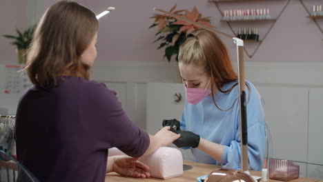 una mujer haciendo una manicura en un salón de uñas.