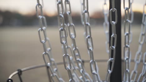 Disc-Golf-Frisbee-Rattles-the-Chains-of-a-Disc-Golf-Basket-|-Slow-Motion-and-Close-Up