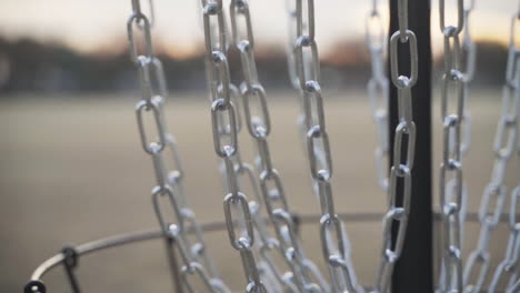 disc golf frisbee hace sonar las cadenas de una canasta de disc golf | cámara lenta y primer plano