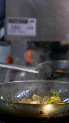 professional chef is cooking mushrooms. cook is preparing mushrooms in a frying pan and pouring sauce on them. delicious food in a restaurant. vertical video