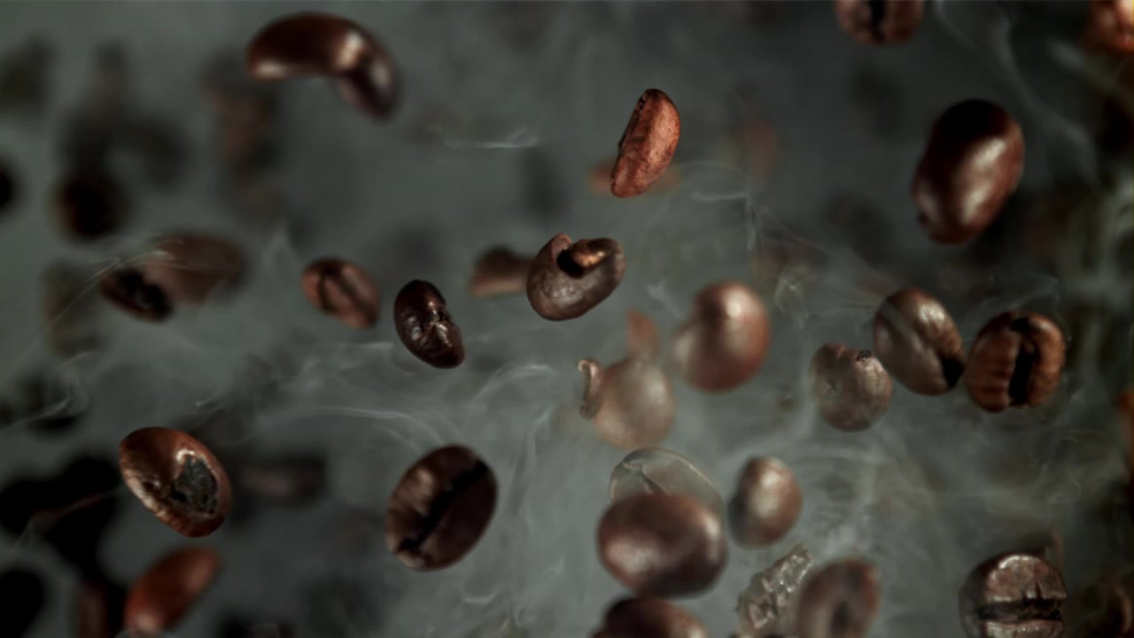 Ristede kaffebønner faller i sakte film med røyk