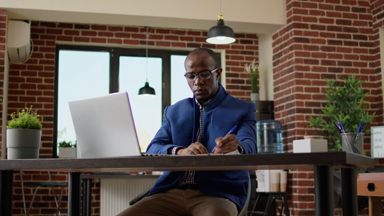 Company worker using documents and research on laptop to take notes