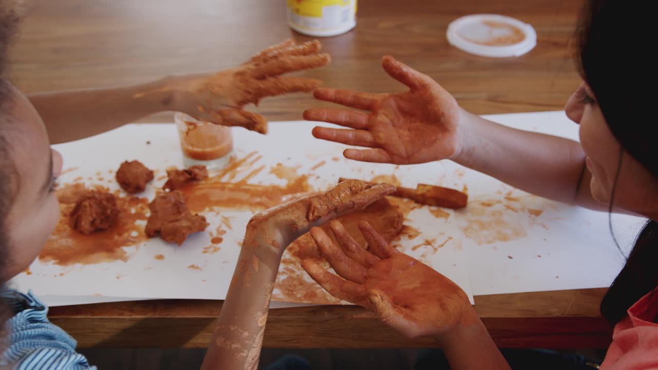 sobre el hombro de dos niñas preadolescentes que se divierten jugando con arcilla de modelado en casa