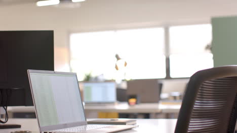 Close-up-of-laptop-on-desk-in-sunny-office,-slow-motion