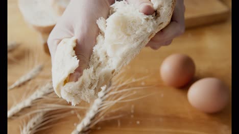 person tearing a piece of fresh bread