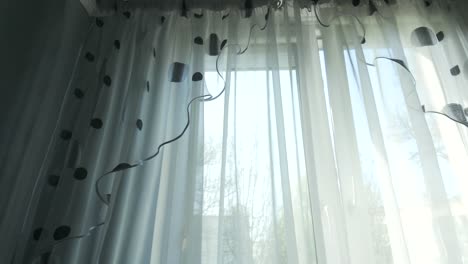 la cortina blanca transparente se mueve contra el viento desde una ventana abierta