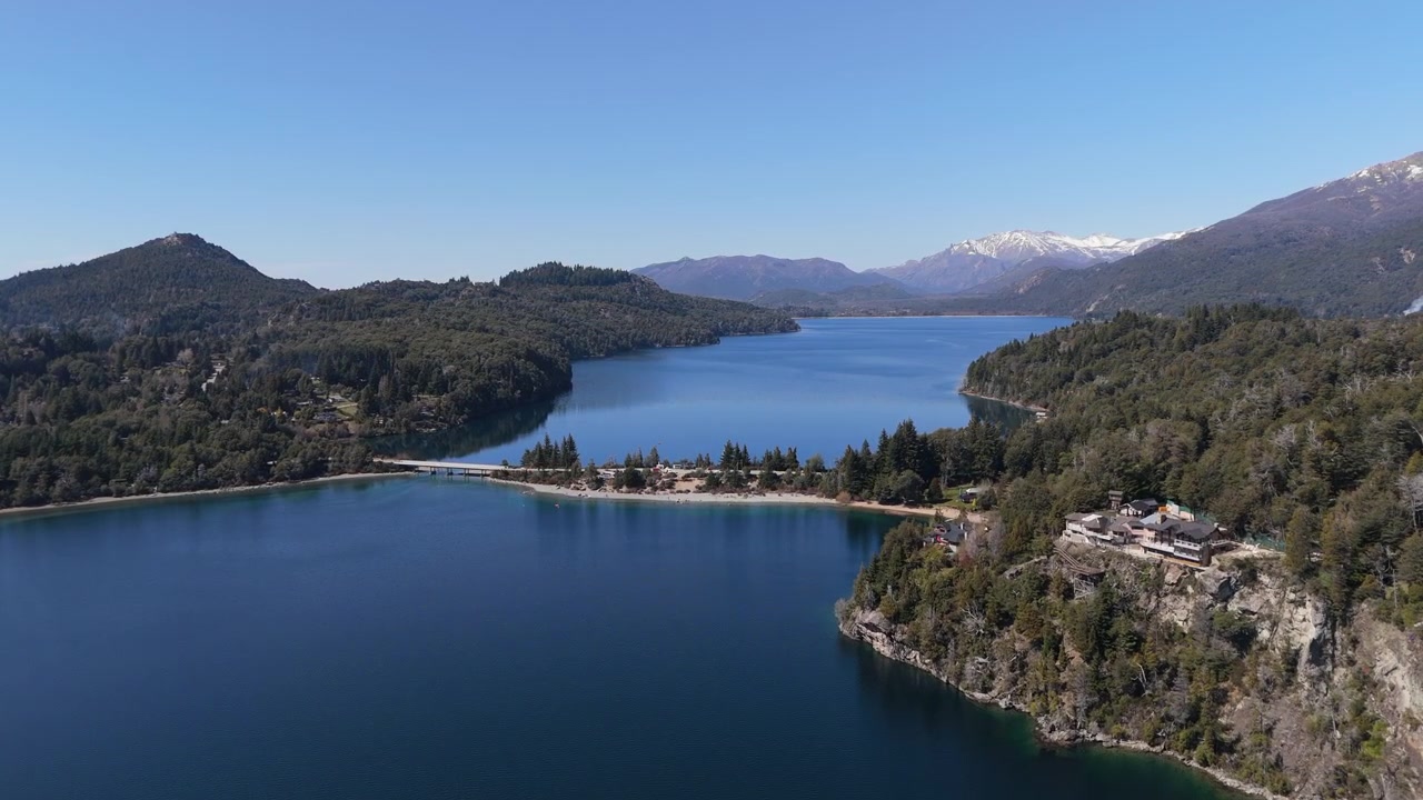 Descida aérea em direção a Playa Sin Viento, Circuito Chico, água azul, floresta verde, Andes cobertos de neve, Bariloche.