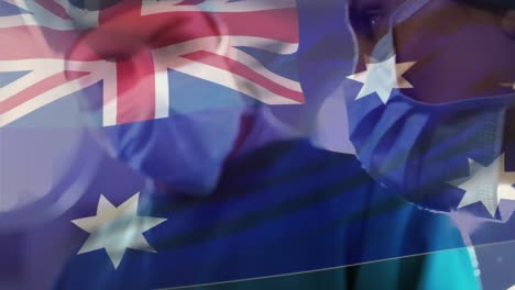 Animation-of-flag-of-australia-over-close-up-of-diverse-doctors-wearing-mask-in-operation-theater