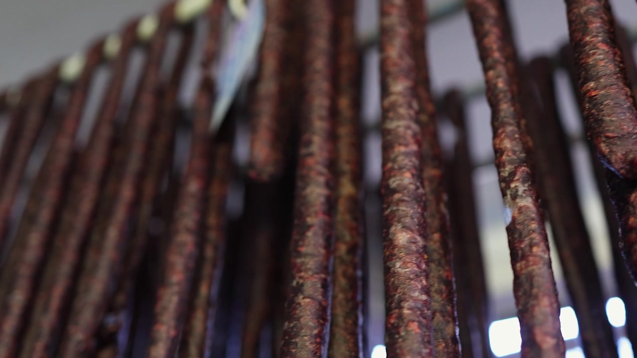 Tomada em ângulo baixo com foco seletivo percorre linguiça Droewors secando