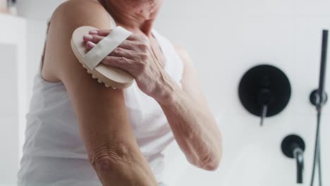 close up of unrecognizable senior woman doing peeling of her arms in the domestic bathroom