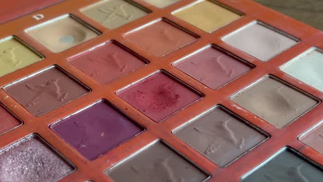 Close-up-fixed-clip-of-make-up-palette-and-soft-brush-picking-up-red-eye-shadow-powder