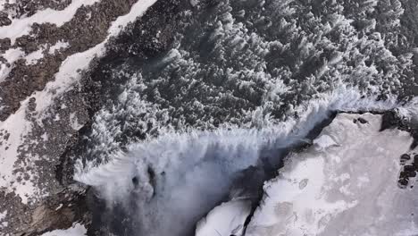 drone view of icy dettifoss waterfall in iceland, frozen cliffs, raging water and scenic winter beauty.