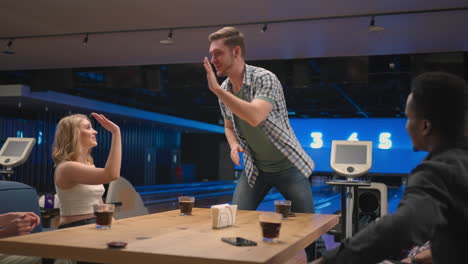 a happy man in a bowling club happily runs to his friends to celebrate the knocked out airstroke. share the victory with friends. multi-ethnic group of friends