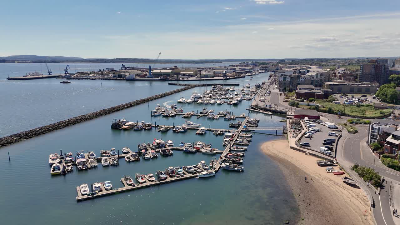 Poole Harbour flight over shallow clear water, fisherman’s marina and dock,old lifeboat station and visitors’ marina looking down Town Quay on bright day