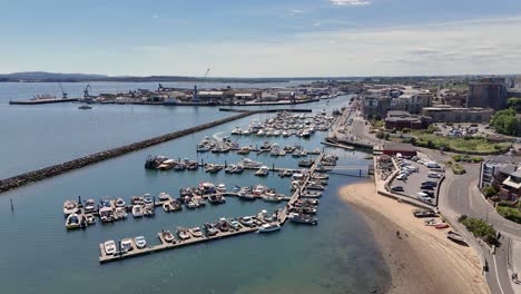 poole harbour flight over shallow clear water, fisherman’s marina and dock,old lifeboat station and visitors’ marina looking down town quay on bright day