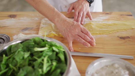 Caucasian-female-chef-teaching-diverse-group-preparing-dishes-and-smiling